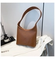 Detailed texture of brown woven hobo bucket bag styled on a white blazer background - Brown
