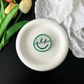 Detail of green smiley face phone grip with mirror finish on white tray with tulips - Dark Green
