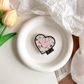Gros plan d'un support de téléphone en forme de cœur avec motifs roses sur une assiette - Style Fleur de Rose Noir Rose