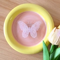 Flachbild einer dekorativen Schale mit Schmetterling für Schmuck auf Holztisch - Rosa