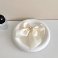 Dettaglio del supporto per telefono a fiocco in raso crema con cristallo a cuore rosa - Bianco Sporco