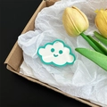 Macro view of a cute cloud-shaped phone grip featuring a smiley face mirror detail - Light Green