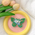 Detail of green butterfly phone stand with sequins and beads on a decorative plate - Green