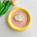 Close-up of cloud-shaped phone grip with smiling face inside a pastel ceramic tray - Yellow