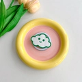 Close-up of cloud-shaped phone grip with a smiley face on a colorful ceramic plate - Dark Green