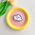 Detail shot of cloud-shaped phone grip with a cute smiley face on a ceramic plate - Deep purple