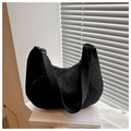 Detail of black dumpling bag with pleated texture and adjustable strap on a book - Black