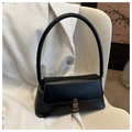 Detalle de bolso negro de cuero sintético con hebilla metálica de bronce en silla blanca - Negro