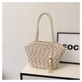 Dettaglio della borsa tote in paglia intrecciata con trame a contrasto e nappa boho - Beige Con Ciondolo