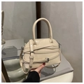 Dettaglio della borsa a mano beige con cinturini decorativi e fibbie metalliche lucide - Cachi