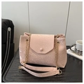 Détail du sac à main rose pâle effet serpent avec chaîne dorée posé sur table - Rose