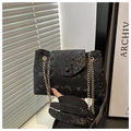 Close-up of black snakeskin texture shoulder bag with elegant gold chain and flap closure - Black