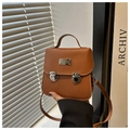 Detailed view of brown PU leather bag featuring double buckle closures and metal plaque - Brown