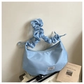 Primer plano de un bolso de nylon azul claro plisado con correa rizada en una maleta - Azul