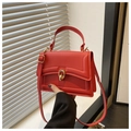 Detail of red minimalist crossbody bag with golden metal twist lock and sleek leather texture - Red