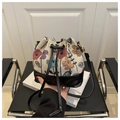 Close-up of vintage floral embroidery fabric and black leather base on drawstring bucket bag - Black