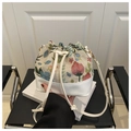 Macro shot of floral tapestry fabric and white leather base on drawstring bucket bag - White