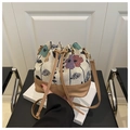 Detail of floral embroidery and brown leather base on a bohemian drawstring bucket bag - Khaki