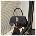 Detalle de solapa brillante con logo S dorado y borla en el bolso de hombro negro - Negro