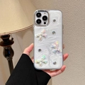 Macro-opname van parelwitte iPhone-hoes met 3D-gekleurde strikken en glanzende strass - Gegalvaniseerd Frame Witte Glitter Laser Strik / iPhone 16