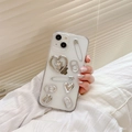 Detail of transparent iPhone case with silver 3D heart, angel, and pull-ring charms - Clear Glitter Heart Angel / iPhone 16