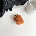 Detailed macro view of plush brown capybara phone stand with soft texture and embroidery - Deep Brown Capybara Side Pose (Black Grip)