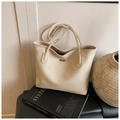 Close-up of cream textured leather tote bag with metal logo and elegant urban styling - White