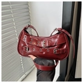 Close-up of deep red leather shoulder bag with punk buckles and metal eyelets - Red