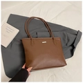 Detalle del bolso tote de cuero granulado marrón con adorno plateado y asas alargadas - Marrón