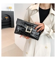 Close-up of black crocodile pattern clutch with a large gold square metal buckle detail - Black