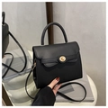 Detail view of black matte leather handbag with gold circular lock and shoulder strap - Black