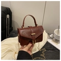 Close-up of a vintage dark brown leather crossbody bag with elegant gold U-shaped buckle - Red