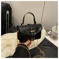 Detail of black glossy faux leather handbag with golden horseshoe buckle and chain strap - Black