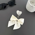 Dettaglio del supporto per telefono a fiocco con cuore di strass e scritta Love incisa - Bianco Sporco