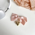 Detail eines rosa Satinbogen-Handyhalters mit einem polierten goldenen Herzanhänger - Rosa
