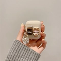 Detalle de funda de AirPods crema con amuleto de café, figura de niña y colgante de concha - Chica de Cereza y Café (Con Colgante de Concha y Perla) / AirPods 1.ª/2.ª generación