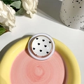 Detail eines weißen ausziehbaren Handy-Griffs mit schwarzem Herz auf Keramiktablett - Magnetischer Typ - Kristallglas - Gepunktetes Herz - Weiß