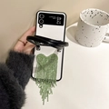 Detail of green rhinestone heart fringe and pearl handle on white quilted phone case - Green Tassel (Samsung ZFlip3)