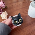 Primer plano de soporte para móvil de gato negro con ojos amarillos en un ambiente acogedor - Negro (Ojos Amarillos)