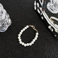 Detail der weißen Perlen-Handykette mit goldenem Karabinerverschluss auf schwarzem Grund - Hummerverschluss 18 Perlen 10mm Perlenkette