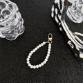 Detailed view of elegant white pearl phone strap with a golden lobster clasp on a dark fabric - Ring Clasp 25 Beads Pearl Chain