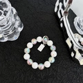 Detail of beaded phone strap with creamy white beads, aurora spheres, and metal tag charm - Laser Beaded String