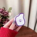 Close-up of a cute purple cartoon face phone grip with mirror on a wooden desk - Deep purple