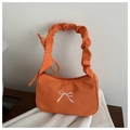 Detalle de bolso de tela naranja con bordado de lazo blanco y asa plisada elegante - Naranja
