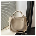 Macro detail of cream-colored leather handbag with gold handle and side accordion folds - White
