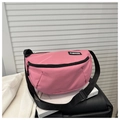 Detalle de bolso medialuna de nailon rosa con correa ajustable y etiqueta de moda - rosa intenso