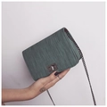 Sac bandoulière vert avec texture brossée et chaîne métallique tenu par un mannequin - Vert