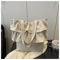 Detail of ruffle trim layers on cream large capacity tote bag on black wood surface - White
