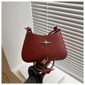 Detailed texture of dark red woven handbag featuring a silver star metal ornament - Red