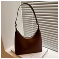 Detail of dark brown hobo shoulder bag with silver buckle on minimalist white books - Brown